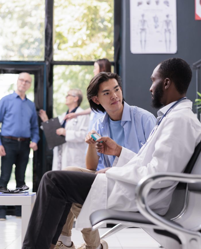 Physician doctor measuring insulin level and glucose in blood sample using glucometer instrument, consulting asian patient. Medic doing medical test during examination in hospital waiting area