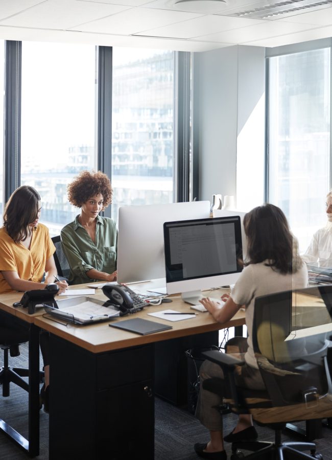 Four female creative colleagues working together in an office, vertical, crop